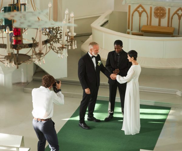 High angle view of wedding ceremony in church with photographer taking pictures on senior couple at altar